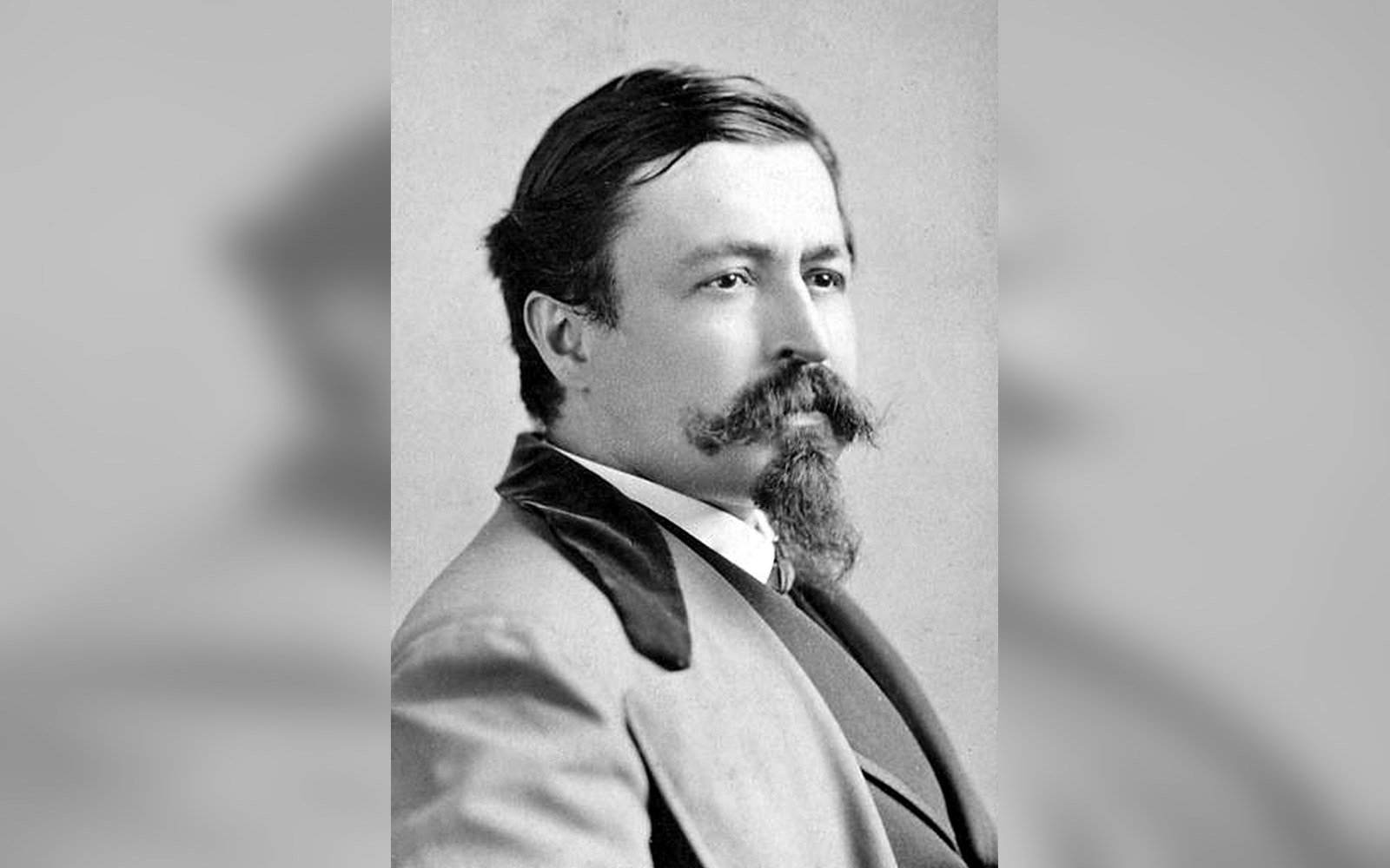 Vintage portrait of a mustached man with a goatee wearing a velvet-collared coat