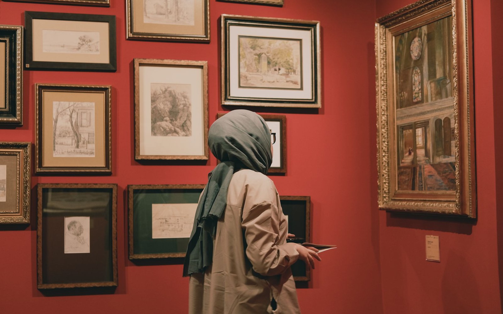 A framed Tenniel wood engraving mounted on a gallery wall, adult visitors standing in front of it at viewing distance